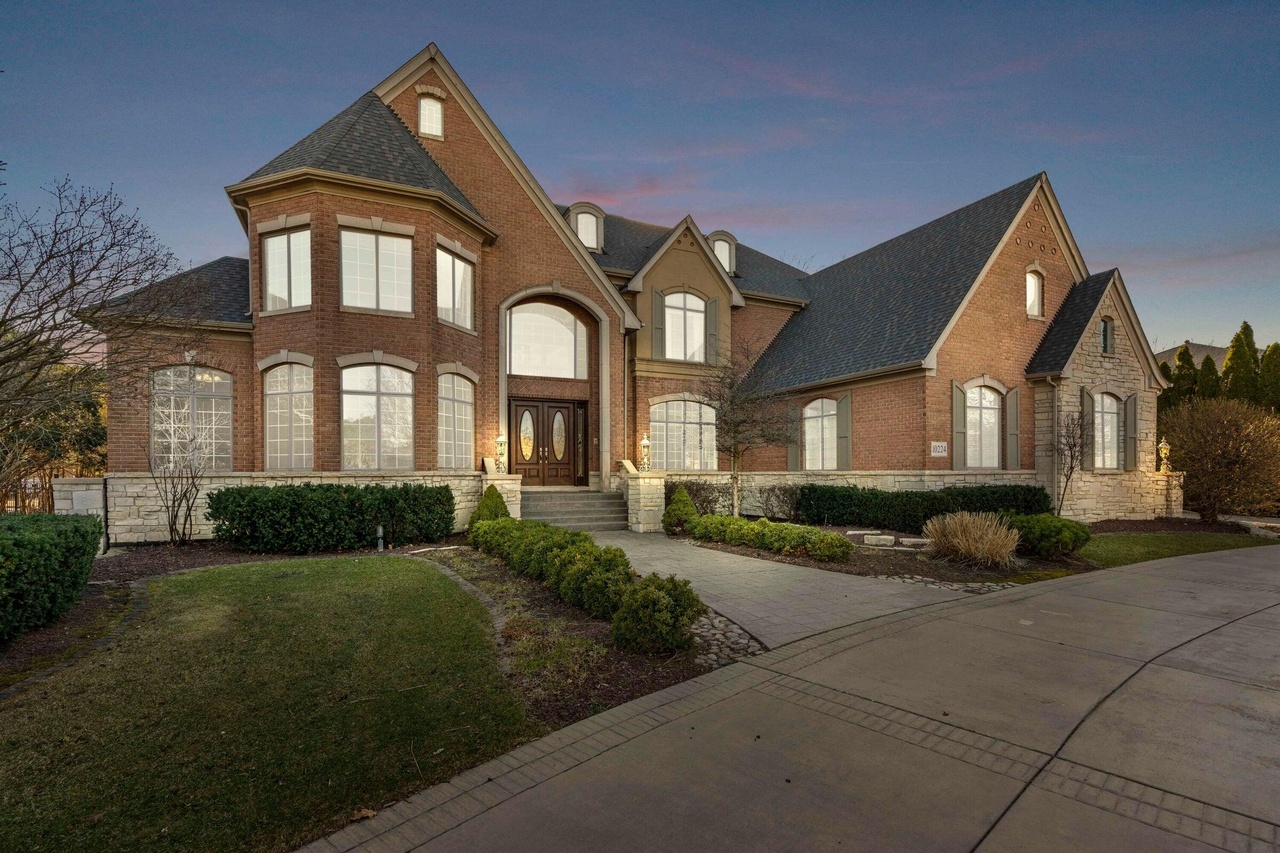Luxury brick estate in Schererville, Indiana featuring custom architecture, grand entryway, premium masonry, and manicured landscaping